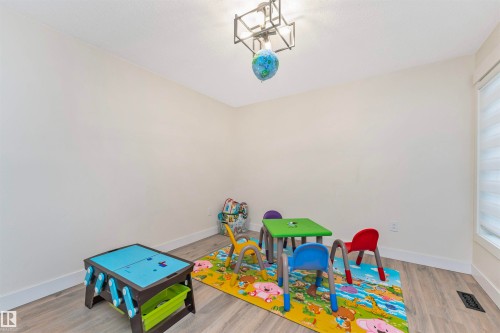 Room featuring light wood-finish flooring, white baseboards, and a contemporary ceiling light fixture - 627 Forest Lane, Edmonton, AB - Indoor Photo Showing Other Room