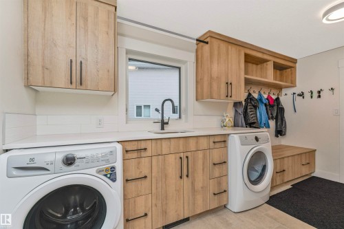 Utility room featuring wood-finish cabinetry, white countertops, and a subway tile backsplash - 627 Forest Lane, Edmonton, AB - Indoor Photo Showing Laundry Room