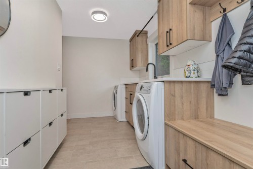 Utility room featuring wood-finish cabinetry, solid surface countertops, and an integrated bench with coat hooks - 627 Forest Lane, Edmonton, AB - Indoor Photo Showing Laundry Room