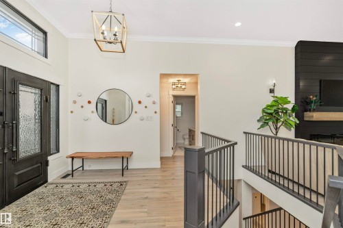 Spacious entryway featuring a decorative double entry door with textured glass, transom windows, wood-finish flooring, a contemporary overhead light fixture, and an open staircase with dark balusters - 627 Forest Lane, Edmonton, AB - Indoor Photo Showing Other Room
