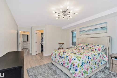 Spacious room featuring light wood-finish flooring, a contemporary sputnik-style ceiling fixture, and a window with white trim - 627 Forest Lane, Edmonton, AB - Indoor Photo Showing Bedroom