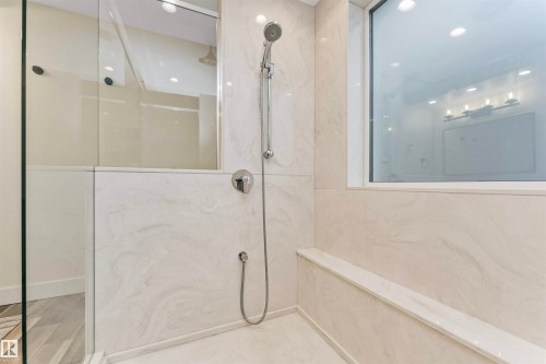 Spacious shower enclosure featuring full-height marble-patterned tile, a built-in bench, and a handheld shower fixture - 627 Forest Lane, Edmonton, AB - Indoor Photo Showing Bathroom
