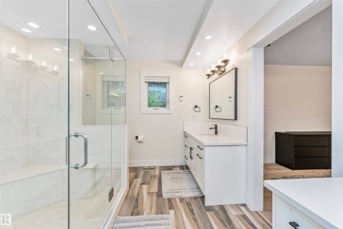Contemporary bathroom featuring a glass-enclosed shower with a built-in bench, a single vanity with a quartz countertop, and wood-finish flooring - 627 Forest Lane, Edmonton, AB - Indoor Photo Showing Bathroom