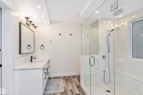 Bathroom featuring a glass-enclosed shower with a built-in bench, white vanity with a countertop, recessed lighting, and wood-finish flooring - 627 Forest Lane, Edmonton, AB - Indoor Photo Showing Bathroom