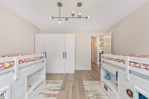 Room featuring wood-finish flooring and a contemporary linear chandelier with spherical glass shades - 627 Forest Lane, Edmonton, AB - Indoor Photo Showing Bedroom