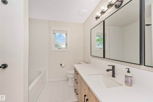 Modern bathroom featuring a wood-finish vanity with ample storage, a white countertop, and an integrated rectangular sink - 627 Forest Lane, Edmonton, AB - Indoor Photo Showing Bathroom