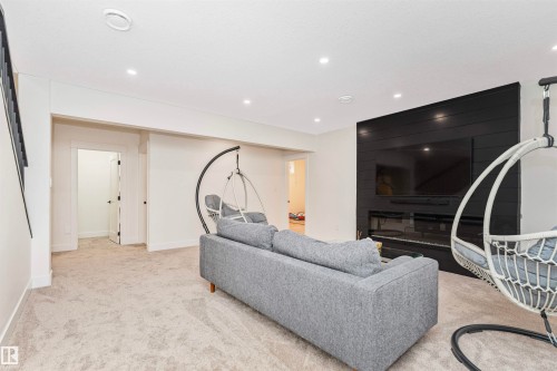 Spacious room featuring light-colored carpeting, recessed lighting, and a modern black shiplap accent wall with a built-in media center - 627 Forest Lane, Edmonton, AB - Indoor