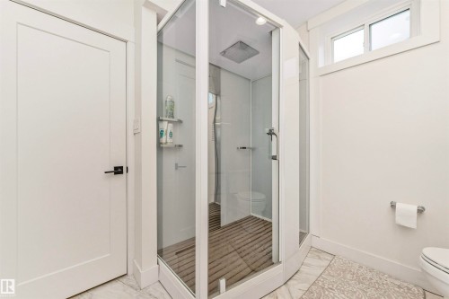 Modern enclosed shower with glass panels, a rain shower head, and slatted wood-finish flooring - 627 Forest Lane, Edmonton, AB - Indoor Photo Showing Bathroom