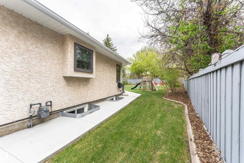 Stucco exterior with a concrete walkway and multiple egress window wells - 627 Forest Lane, Edmonton, AB - Outdoor