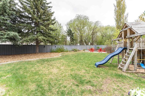 Expansive backyard featuring a large lawn area, mature evergreen trees, and a full-height privacy fence - 627 Forest Lane, Edmonton, AB - Outdoor With Backyard