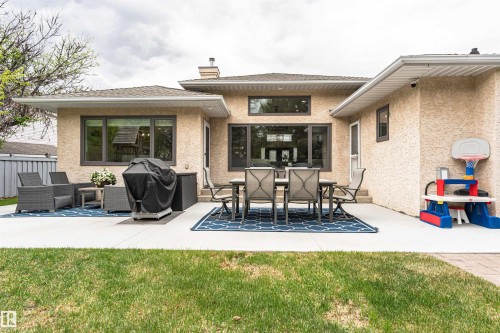 Expansive concrete patio with multiple defined areas, stucco exterior, and a manicured lawn - 627 Forest Lane, Edmonton, AB - Outdoor With Deck Patio Veranda