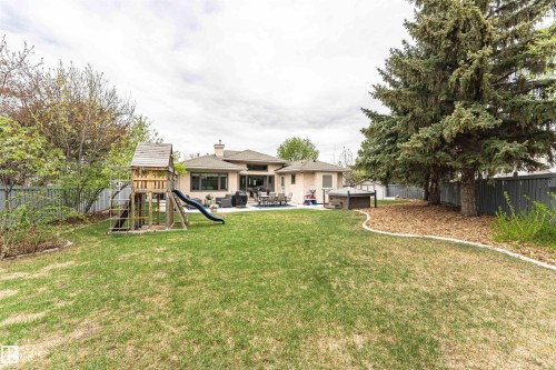 Expansive backyard featuring a manicured lawn, a large patio area, and mature trees - 627 Forest Lane, Edmonton, AB - Outdoor With Deck Patio Veranda