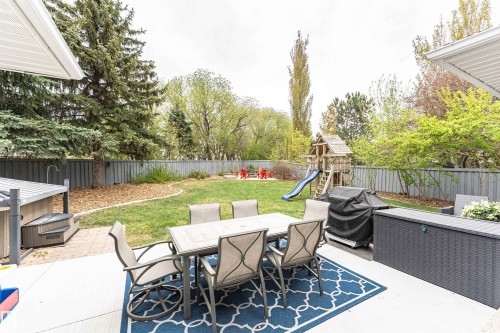 Spacious backyard featuring a large concrete patio, expansive lawn, mature perimeter trees, and a privacy fence - 627 Forest Lane, Edmonton, AB - Outdoor With Deck Patio Veranda