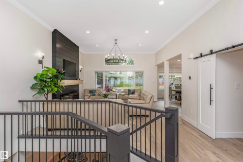 Vaulted great room featuring a shiplap fireplace, wood-finish flooring, and a contemporary chandelier - 627 Forest Lane, Edmonton, AB - Indoor Photo Showing Other Room