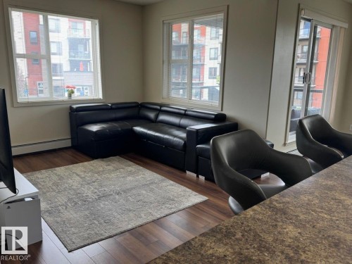 Living area featuring wood-finish flooring, white baseboards, and neutral wall tones - 228 308 Ambleside Link Sw, Edmonton, AB - Indoor