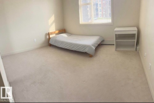 Room featuring light-toned carpeting, neutral wall paint, and a window with blinds - 228 308 Ambleside Link Sw, Edmonton, AB - Indoor Photo Showing Bedroom