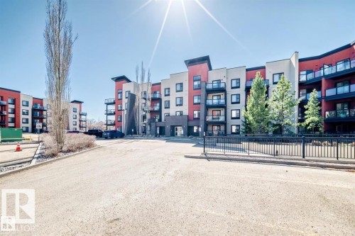 Modern multi-story residential building featuring a vibrant red and light-colored facade - 228 308 Ambleside Link Sw, Edmonton, AB - Outdoor With Balcony With Facade