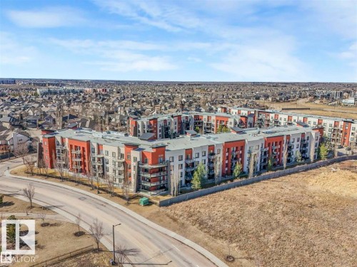 Modern apartment complex featuring a multi-story design with prominent red and light gray facades - 228 308 Ambleside Link Sw, Edmonton, AB - Outdoor With View