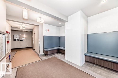 Building lobby featuring a built-in seating area with upholstered backrests and wood-finish bases, large format floor tiles, and recessed lighting - 228 308 Ambleside Link Sw, Edmonton, AB - Indoor