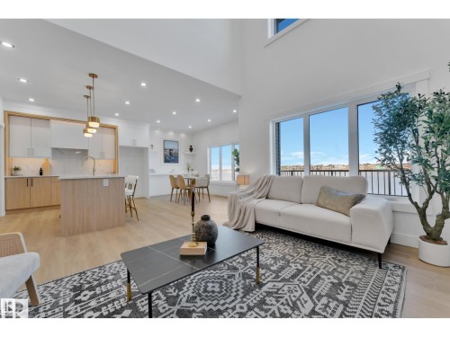 Open-concept living area featuring high ceilings, large windows, wood-finish flooring, recessed lighting, and a kitchen island with pendant lighting - 1129 Starling Drive, Edmonton, AB 