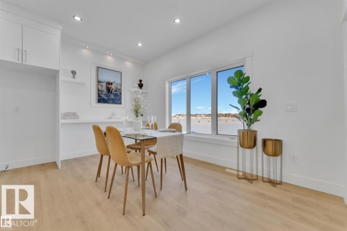 Bright dining area featuring a large picture window, recessed lighting, and light wood-finish flooring - 1129 Starling Drive, Edmonton, AB 