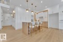Kitchen featuring a center island with pendant lighting, white upper cabinetry, and wood-finish lower cabinetry - 1129 Starling Drive, Edmonton, AB 