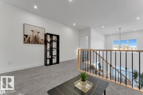 Loft area featuring grey carpet flooring, white walls, recessed lighting, and a modern stair railing with natural wood handrails and black metal spindles - 1129 Starling Drive, Edmonton, AB 