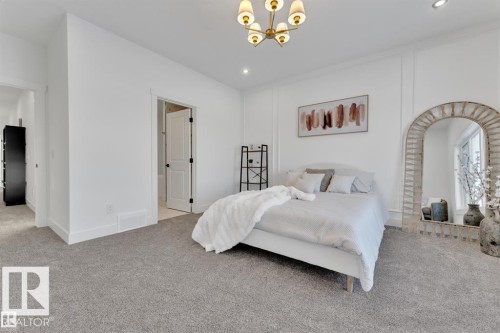 Spacious room featuring light gray carpeting, crisp white walls, and a contemporary chandelier - 1129 Starling Drive, Edmonton, AB 