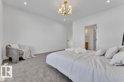 Spacious room featuring neutral carpet, recessed lighting, and a modern gold-finish chandelier - 1129 Starling Drive, Edmonton, AB 