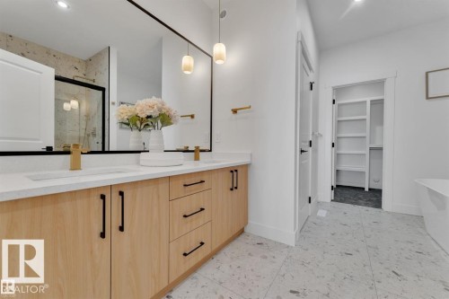 Dual vanity with light wood-finish cabinetry, white countertops, and gold-tone fixtures - 1129 Starling Drive, Edmonton, AB 