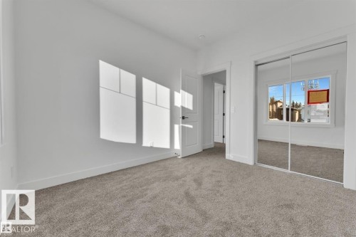 Carpeted room featuring a white interior door with contemporary hardware and mirrored bi-fold closet doors - 1129 Starling Drive, Edmonton, AB 