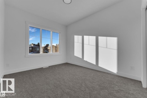 Bright interior space featuring a multi-pane window, neutral carpet flooring, white painted walls, and white trim - 1129 Starling Drive, Edmonton, AB 