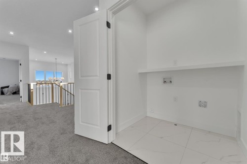 Dedicated laundry area featuring white tile flooring, a built-in shelf, and essential utility hookups - 1129 Starling Drive, Edmonton, AB 
