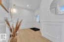 Entryway featuring light wood-finish flooring, white paneled wainscoting, and a white front door with decorative glass inserts - 1129 Starling Drive, Edmonton, AB 