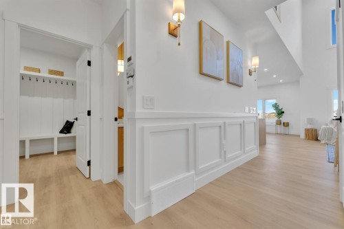 Foyer with wood-finish flooring, wainscoting details, and modern wall sconces - 1129 Starling Drive, Edmonton, AB 