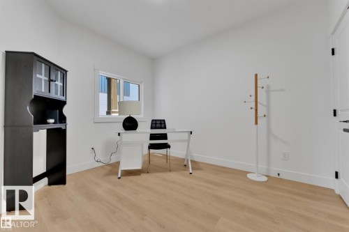 Bright room featuring light wood-finish flooring, white baseboards, and a single window with white trim - 1129 Starling Drive, Edmonton, AB 