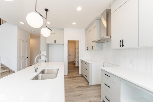 The kitchen features light-toned cabinetry, light countertops, and a subway tile backsplash - 2355 Egret Way, Edmonton, AB - Indoor Photo Showing Kitchen With Double Sink
