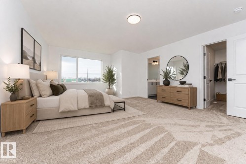 Spacious room featuring light-colored walls, carpeted flooring, and a large window providing natural light - 2355 Egret Way, Edmonton, AB - Indoor Photo Showing Bedroom