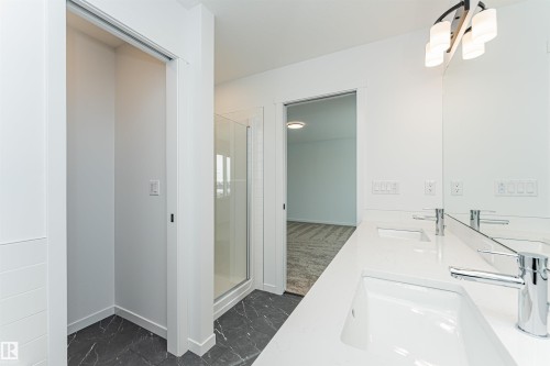 Bathroom featuring a double vanity with two rectangular sinks, chrome faucets, and a large mirror - 2355 Egret Way, Edmonton, AB - Indoor Photo Showing Bathroom