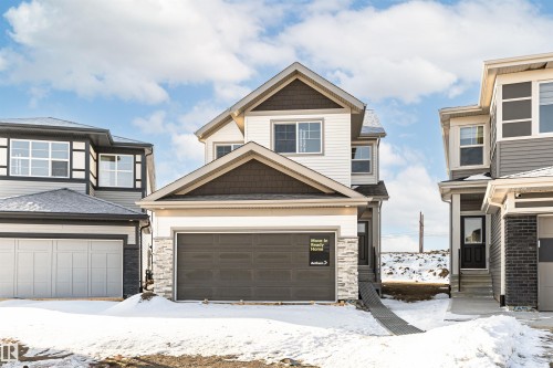 The property features light-colored siding with dark accents, a two-car garage, and a covered entry - 2355 Egret Way, Edmonton, AB - Outdoor With Facade
