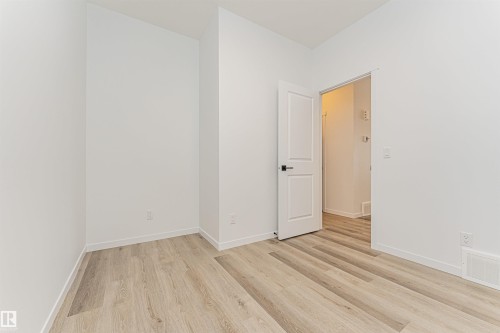 This room features light-toned plank flooring and crisp white walls, providing a neutral aesthetic - 2355 Egret Way, Edmonton, AB - Indoor Photo Showing Other Room