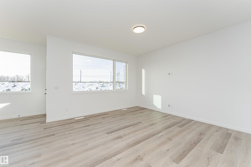 Spacious room featuring light wood flooring, white walls, and large windows providing ample natural light - 2355 Egret Way, Edmonton, AB - Indoor Photo Showing Other Room