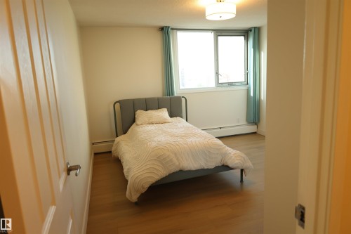Room featuring wood-finish flooring, a large window, and a ceiling-mounted light fixture - 807 10011 116 Street, Edmonton, AB - Indoor Photo Showing Bedroom