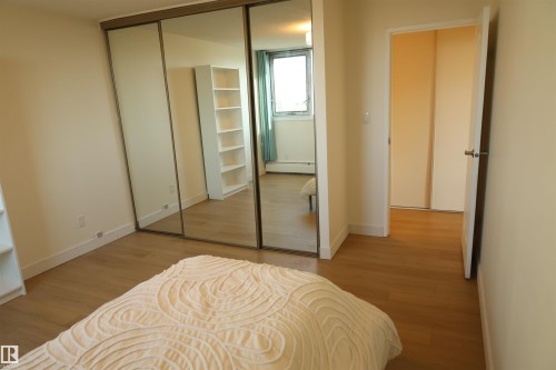 Room featuring wood-finish flooring, mirrored sliding closet doors, and neutral wall tones - 807 10011 116 Street, Edmonton, AB - Indoor Photo Showing Bedroom