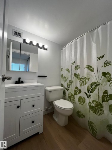 Bathroom featuring a white vanity with black hardware, coordinating black faucet, and a wall-mounted medicine cabinet with integrated lighting - 807 10011 116 Street, Edmonton, AB - Indoor Photo Showing Bathroom