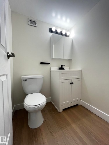 Powder room featuring a white single-sink vanity with matte black hardware, a black wall-mounted faucet, and a mirrored medicine cabinet - 807 10011 116 Street, Edmonton, AB - Indoor Photo Showing Bathroom