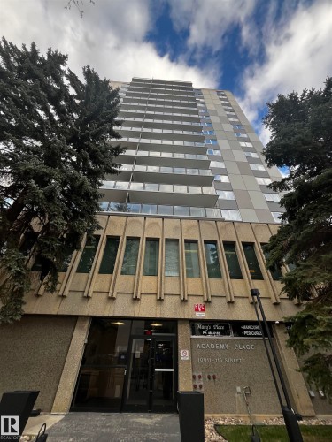 Multi-story building featuring individual balconies with clear panels, a textured concrete lower facade, and a prominent main entrance - 807 10011 116 Street, Edmonton, AB - Outdoor
