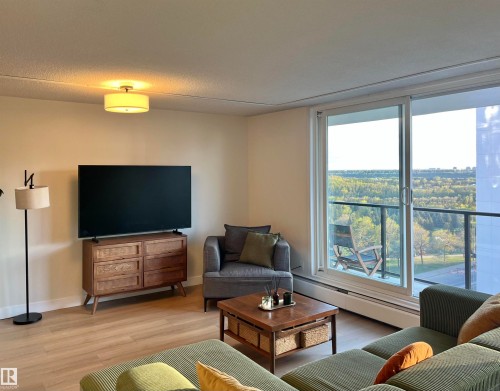 Living area with wood-finish flooring, a contemporary ceiling light fixture, and a sliding glass door leading to an outdoor balcony - 807 10011 116 Street, Edmonton, AB - Indoor Photo Showing Living Room