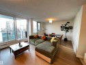 Spacious living area featuring large windows, wood-finish flooring, a ceiling-mounted light fixture, and a dedicated dining space - 807 10011 116 Street, Edmonton, AB  - Indoor Photo Showing Living Room 