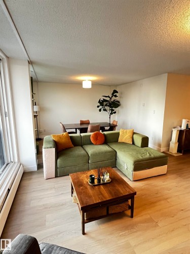 Open-concept living area featuring light wood-finish flooring, white walls, and a large window - 807 10011 116 Street, Edmonton, AB - Indoor Photo Showing Living Room